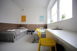 a bedroom with a bed and a yellow chair at Sport Hostel Chodakowska Warszawa in Warsaw