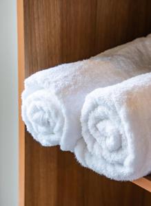 a stack of white towels on a shelf at La Pearl Mathiveri in Mathiveri +61 photos
