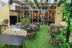 a room with tables and chairs and green grass at Capital M by BednBeyond Dehali Line, Westlands Nairobi, Kenya in Nairobi