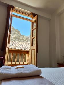 Un dormitorio con una ventana con vista a la montaña. en Qente Wings, en Ollantaytambo
