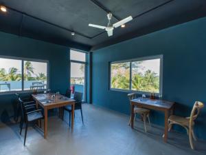 a dining room with blue walls and tables and chairs at La Pearl Mathiveri in Mathiveri