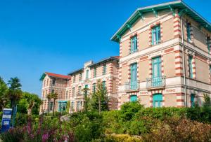 a large brick building with blue windows at Résidence de Tourisme Vacances Bleues Villa Regina in Arcachon