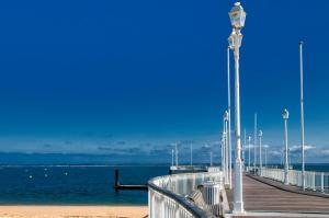a pier with benches and a light pole on the beach at Résidence de Tourisme Vacances Bleues Villa Regina in Arcachon