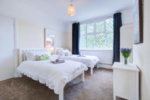 KentにあるNewly Refurbished 2 Bedroom Houseのベッドが2つと窓がある白い部屋
