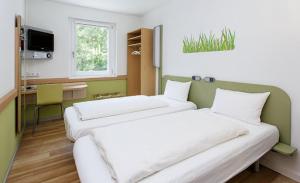 a room with two beds and a desk in it at ibis budget Flensburg Handewitt in Handewitt