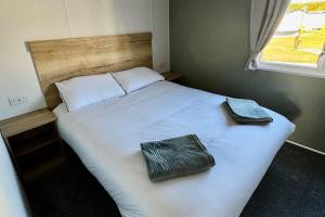 a bedroom with a white bed with two towels on it at Sea La Vie Caravan at Silver Sands Holiday Park in Lossiemouth +17 photos