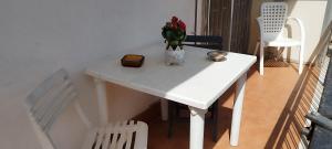 Una mesa blanca con un jarrón de flores. en A casa di Naty, en Gravina di Catania