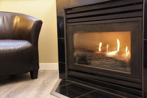 a living room with a fireplace and a chair at Alpenglow Lodge by MVA in Whistler