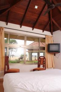 a bedroom with a bed and two chairs and a window at Malpe Sea Front Cottages in Udupi