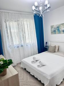 a bedroom with a large white bed with a chandelier at EM House in Otopeni