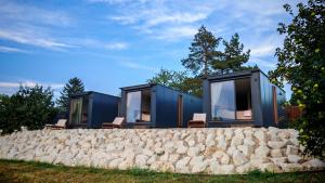 a house with a stone wall and windows at Casa Slarku - Luxury Container Houses in Miskolc