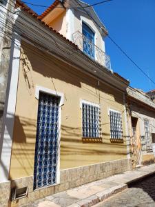 a yellow building with blue windows on a street at Casarão da Alê - Cama 1 in Carmo +4 photos