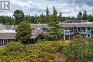 an aerial view of a large building with trees at Aloha Cottage, Nanoose Bay - 2 Bdrm Oceanfront Unit with Private Deck in Nanoose Bay