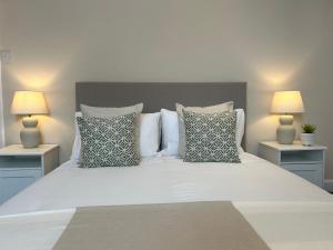 a white bed with pillows and two lamps at Herring House in Berwick-Upon-Tweed +13 photos