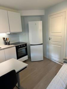 a kitchen with a white refrigerator and a white door at Small studio with everything you need in Tromsø