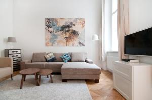 een woonkamer met een bank en een tv bij HeyMi Apartments Oper in Wenen