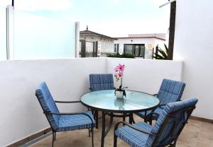 a table with chairs and a vase with flowers on a balcony at Almina in Corralejo