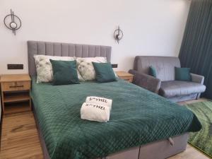 sypialnia z łóżkiem z zieloną kołdrą i krzesłem w obiekcie SkyHel Apartamenty 101 w mieście Hel