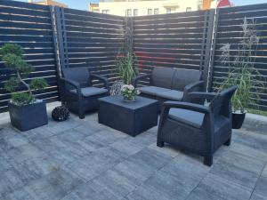 patio z krzesłami, stołami i ogrodzeniem w obiekcie SkyHel Apartamenty 101 w mieście Hel