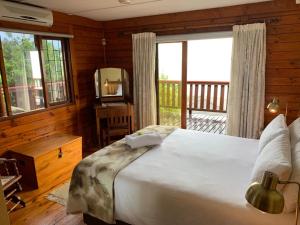a bedroom with a large bed and a large window at Bay View Cabin in Gordonʼs Bay