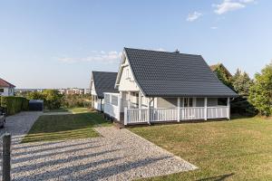 a white house with a black roof and a yard at Mazurskie Wzgórze - domki całoroczne HOME APART in Ostróda