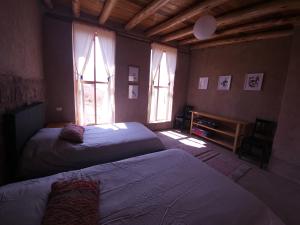two beds in a room with two windows at Pampachayoq - Mountain retreat in Urubamba