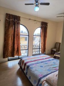 a bedroom with a bed and two large windows at Departamento frente a palacio gobierno in Lima