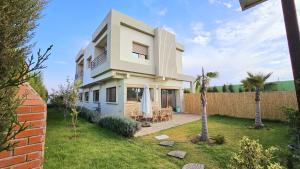 a white house with a fence and palm trees at fancy house surf camp in Douar Debra