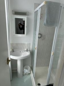 a person taking a picture of a bathroom with a sink and shower at The Stage Door Hotel in Blackpool