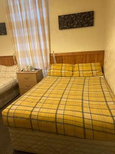 a bedroom with a bed with a yellow plaid blanket at The Stage Door Hotel in Blackpool