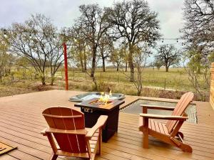 a wooden deck with two chairs and a fire pit at Draco at the Retreat in Fredericksburg