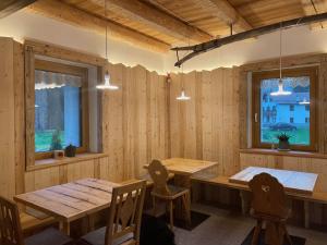 a dining room with two tables and two windows at Locanda al Toal in Moena