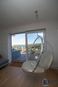 a swinging chair in a room with a large window at Ultimate Coastal Escape - Stylish & Estuary Views in Salcombe +24 photos