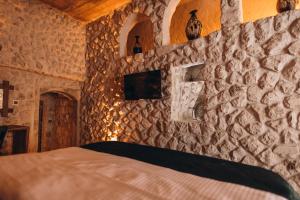 ネヴシェヒルにあるİsadora Cave Cappadociaの石壁のベッドルーム(ベッド付)