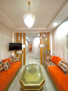 a living room with orange couches and a flat screen tv at appartement 1 chambre Centre ville in Agadir