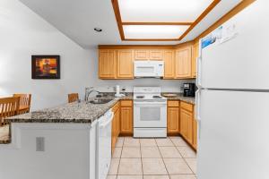 Una cocina con electrodomésticos blancos y gabinetes de madera. en Greens at Copper 317 by Summit County Mountain Retreats, en Copper Mountain