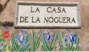 ein Schild an der Seite einer Wand mit Blumen in der Unterkunft Casas rurales Casa Noguera 2 in La Casa de la Noguera + 2 Fotos