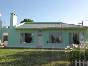 a green house with a fence in front of it at La Querencia - El Cóndor in Balneario El Condor