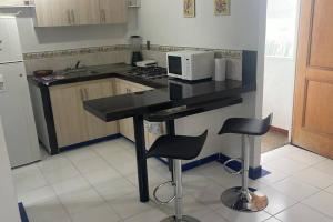 a kitchen with a counter with two stools and a microwave at Apartamento acogedor - Melgar in Guaduala