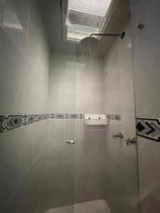 Un baño con ducha con puerta de cristal. en Bamuka Hostal, en Bogotá