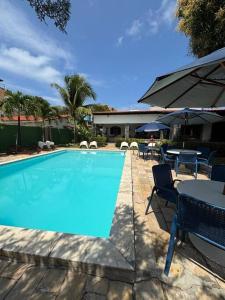 a swimming pool with a table and chairs and an umbrella at Ampla casa de 3 quartos com piscina em Serrambi PE a 50mts do mar in Porto De Galinhas