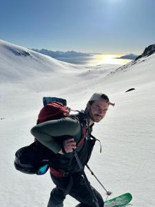 a man on skis with a backpack on a snow covered slope at Cozy small house with amazing view in Hennes