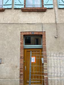 un edificio con una puerta de madera y una ventana en Loft Bohème et Cosy, en Montauban