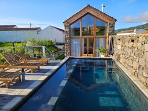 a swimming pool with benches and a house at Casa do Cinzeiro, Açores - With private pool! in Nordeste