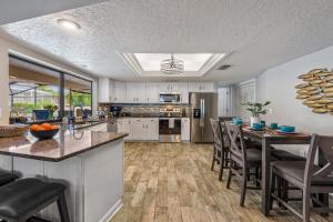 a kitchen with white cabinets and a table with chairs at Bradenton Vacation Home with Heated Pool, Hot Tub & Game Room Near Anna Maria Island in Bradenton