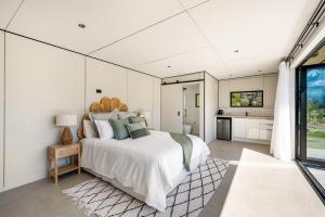 a bedroom with a large bed and a kitchen at Riverbank by Sothebys Luxury Rental Homes in Wanaka +23 photos