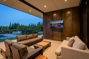 a living room with two couches and a tv on a wall at Riverbank by Sothebys Luxury Rental Homes in Wanaka