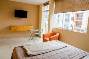 a bedroom with a bed and a chair and a television at TruGarden Hotel Trujillo in Trujillo