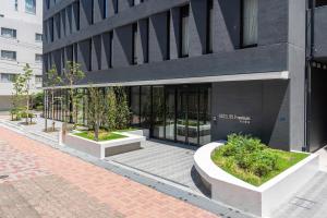 市川市にあるHOTEL R9 Premium Ichikawaekimaeの前に植物が何本か見える建物