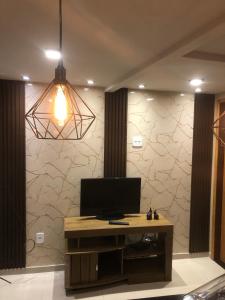 a living room with a television and a wall at Recanto Cabocla II in Arraial do Cabo